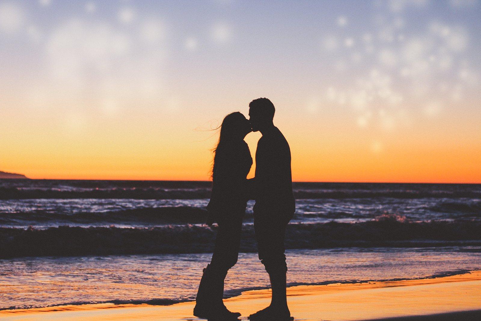 A sunset beach silhouette with soft warm bokeh circles scattered across the sky